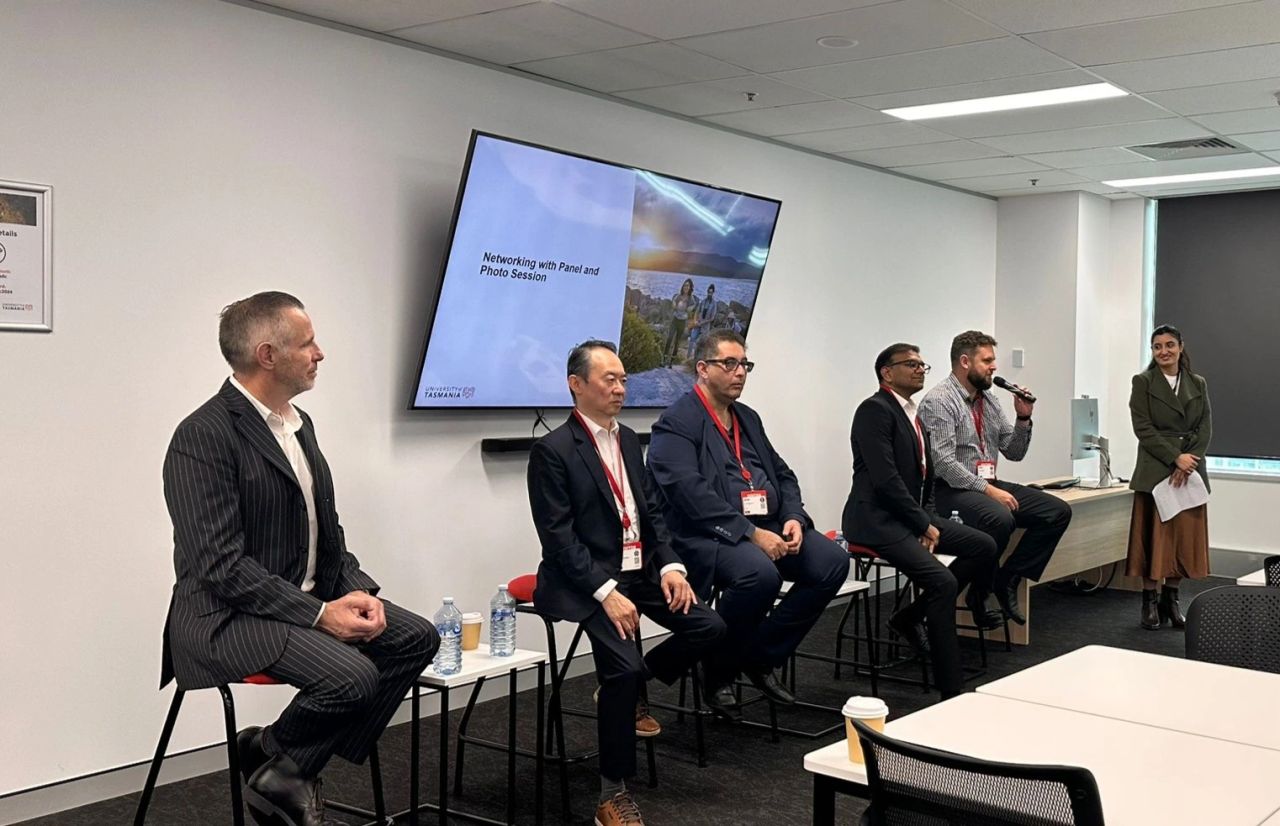 Five industry panelists seated on stools at the University of Tasmania Sydney campus Industry Fireside Chat, a discussion on employability, leadership, and career development with a student moderator on the right introducing the networking and photo session segment