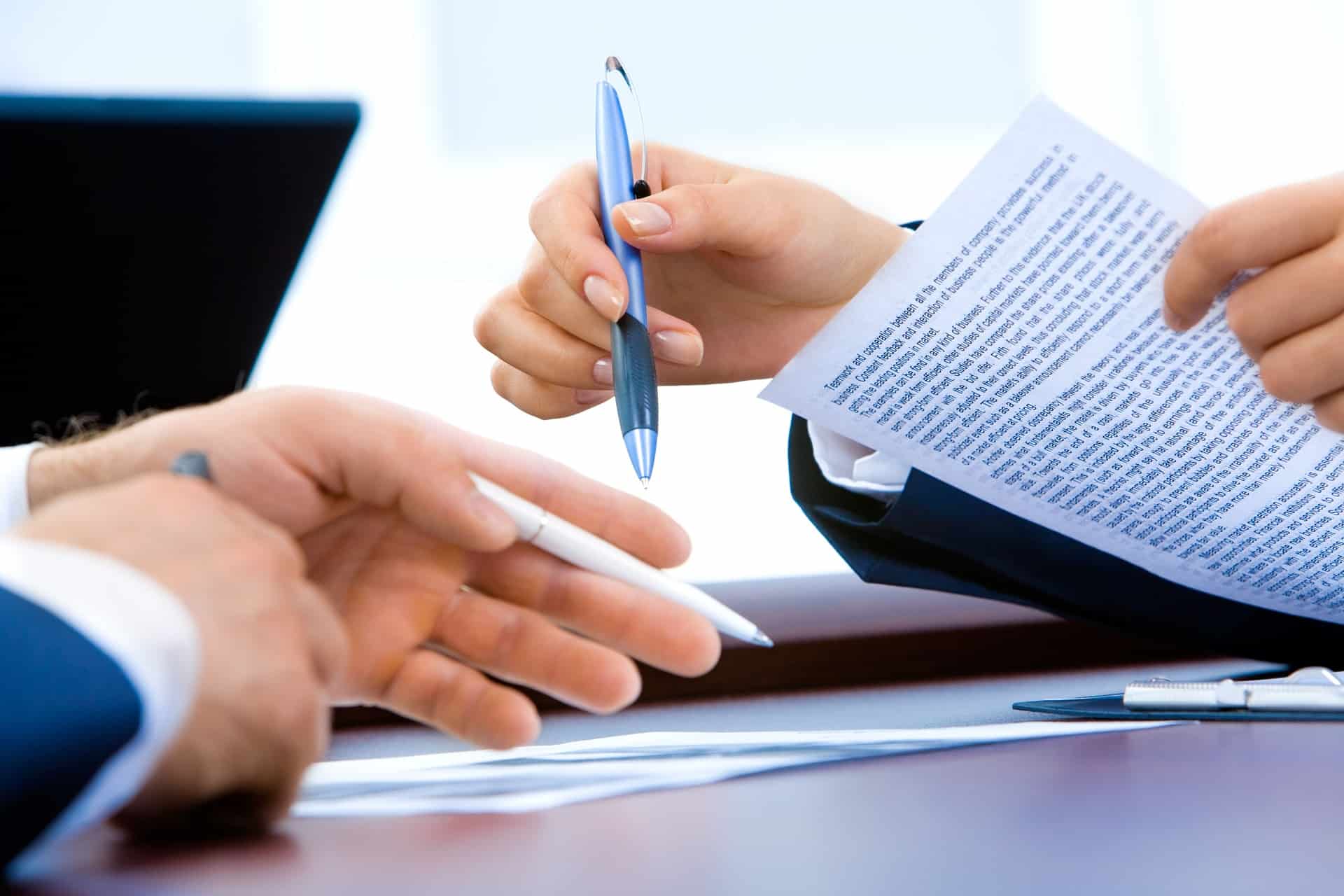 hands of two people talking while holding a paper and pen