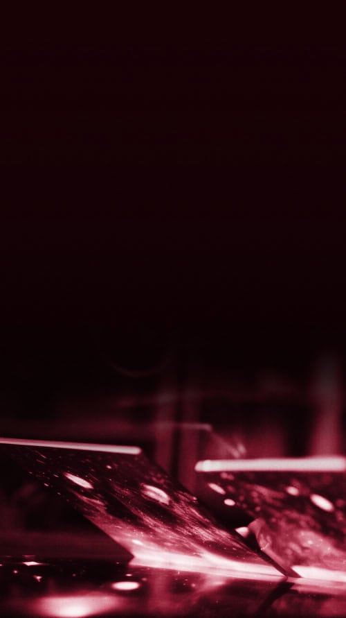laptops that are partially opened with red aura coming out of it against a black background